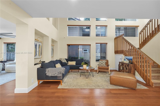 living room with a towering ceiling, hardwood / wood-style flooring, and ceiling fan