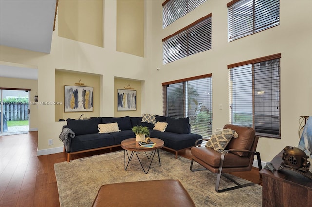 living room with a towering ceiling and dark wood-type flooring