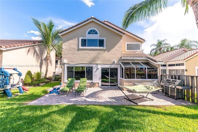 rear view of house featuring a yard, a patio area, and a sunroom