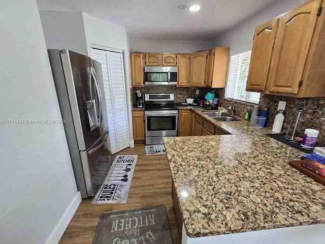 kitchen with kitchen peninsula, stainless steel appliances, tasteful backsplash, and dark hardwood / wood-style floors