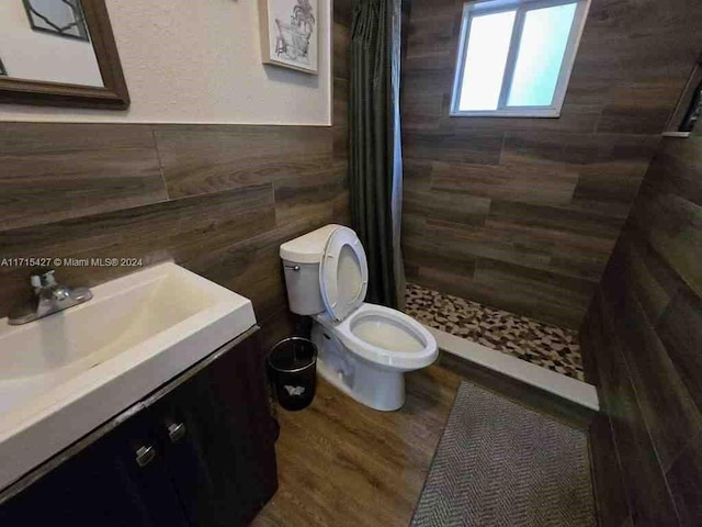 bathroom with tiled shower, hardwood / wood-style floors, vanity, and toilet