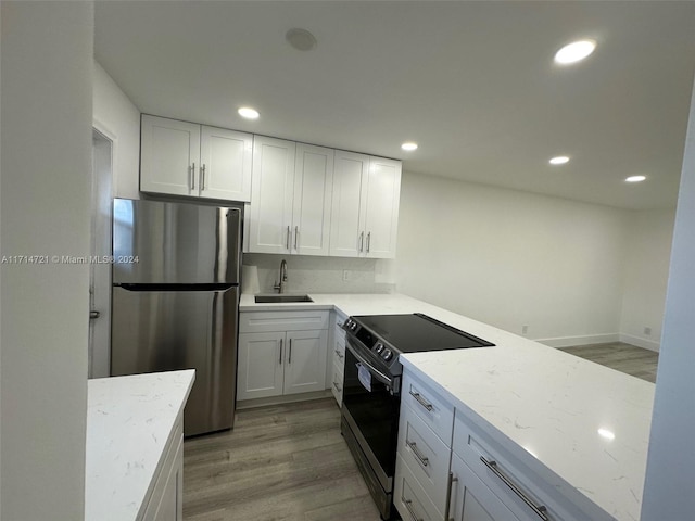 kitchen featuring light stone counters, stainless steel appliances, sink, light hardwood / wood-style flooring, and white cabinetry