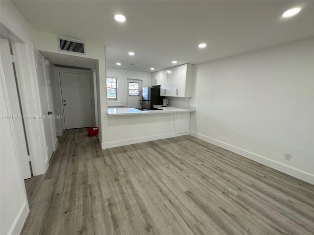 kitchen featuring white cabinets, stainless steel fridge, kitchen peninsula, and light hardwood / wood-style flooring