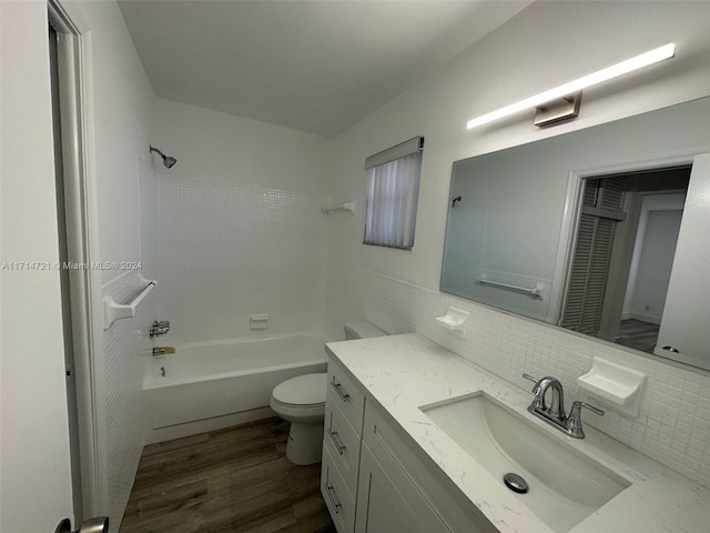 full bathroom featuring tasteful backsplash, wood-type flooring, toilet, vanity, and tiled shower / bath