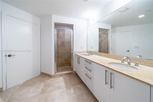 bathroom with double vanity, a shower stall, visible vents, and a sink