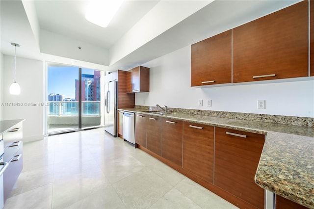 kitchen featuring pendant lighting, a city view, brown cabinets, stainless steel appliances, and a sink