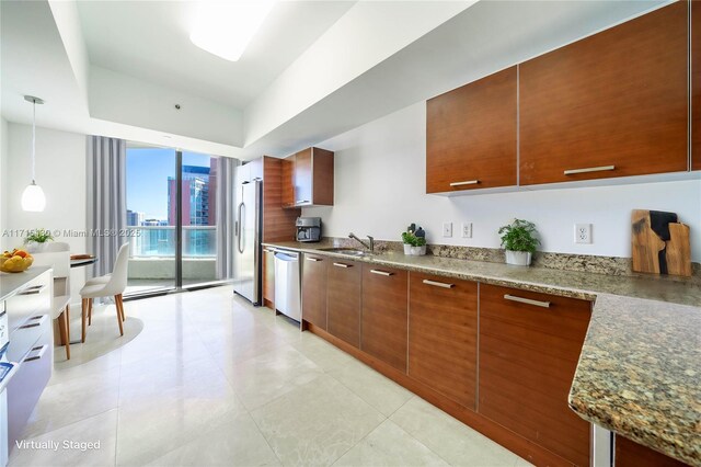 kitchen with stainless steel appliances, dark stone countertops, pendant lighting, expansive windows, and sink