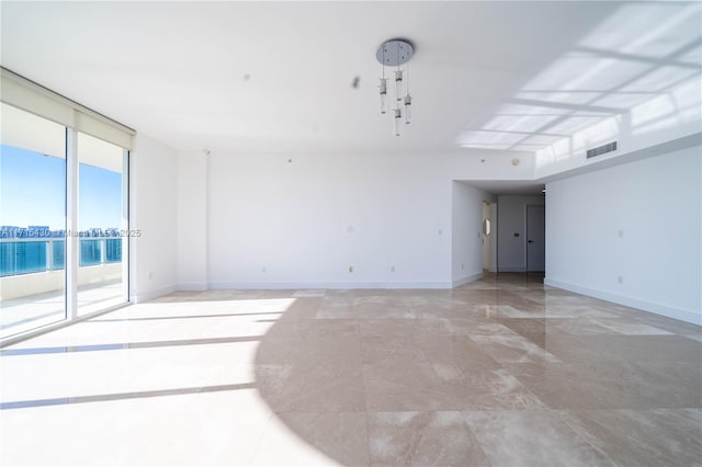 empty room with a wall of windows, visible vents, and baseboards