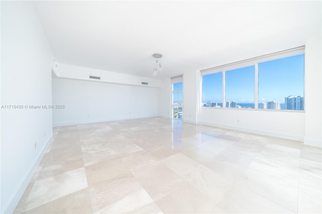 empty room featuring a view of city, visible vents, and baseboards