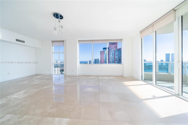 empty room featuring a view of city, visible vents, and baseboards