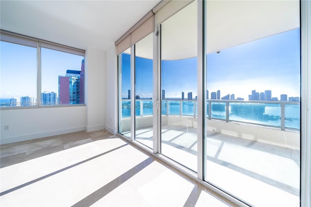 unfurnished room featuring a water view, baseboards, and a city view