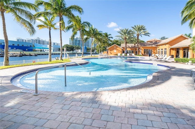 community pool featuring a patio, a water view, and fence