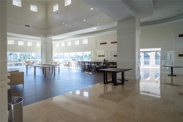 interior space with visible vents, a towering ceiling, decorative columns, and a decorative wall