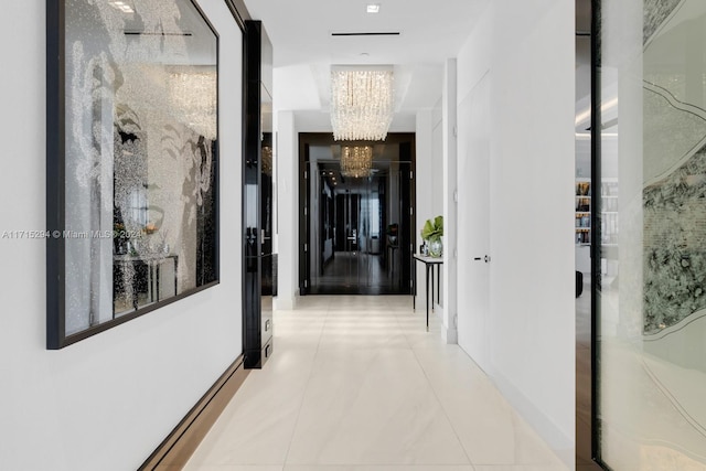 hallway with a chandelier and tile patterned flooring