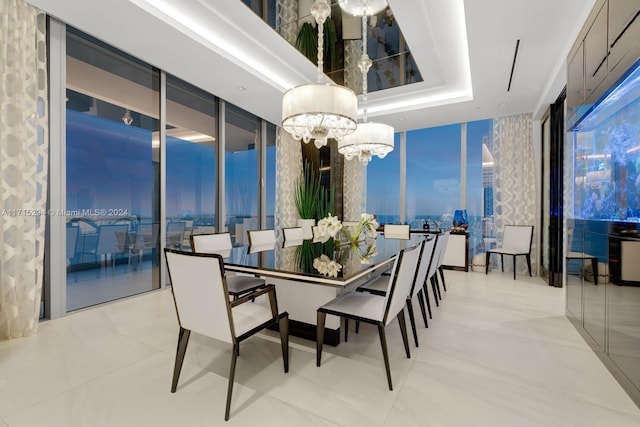 dining area with a tray ceiling, a wall of windows, and a notable chandelier