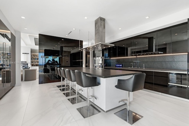 kitchen with sink, a kitchen breakfast bar, island exhaust hood, a spacious island, and light tile patterned floors