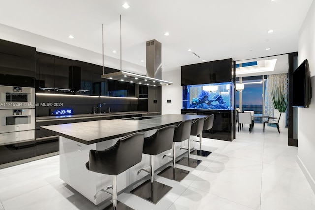 kitchen with a breakfast bar, sink, decorative light fixtures, a kitchen island, and island exhaust hood