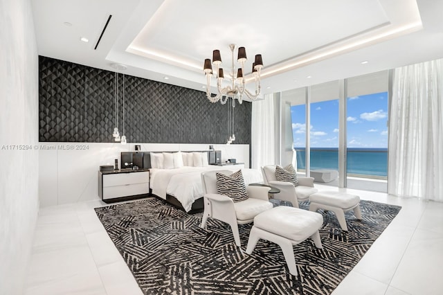 bedroom featuring tile patterned floors, expansive windows, a water view, a tray ceiling, and a chandelier