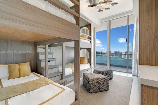 bedroom with access to outside, a water view, and floor to ceiling windows