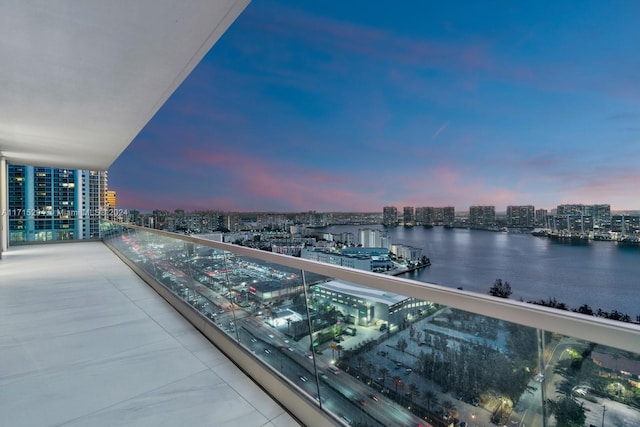 balcony at dusk featuring a water view