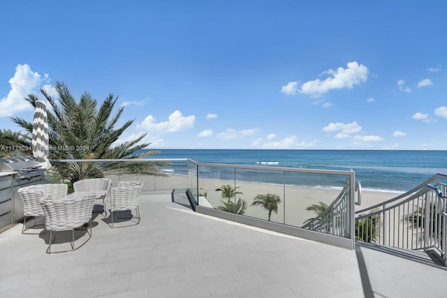 view of patio / terrace featuring a grill, a water view, and a view of the beach