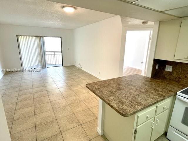 kitchen featuring decorative backsplash, electric stove, and kitchen peninsula