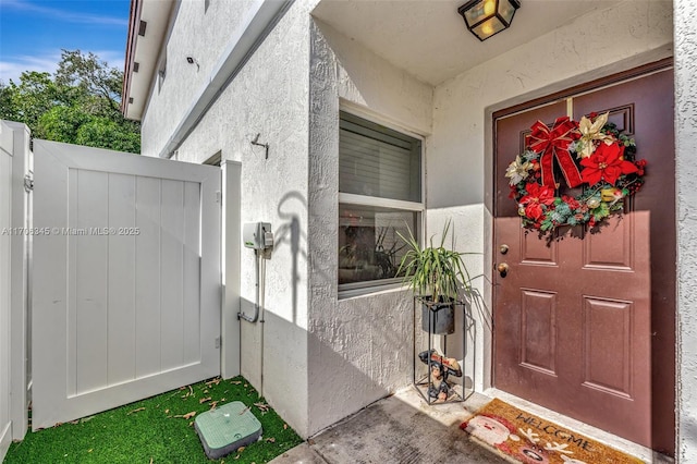 property entrance featuring a gate and stucco siding