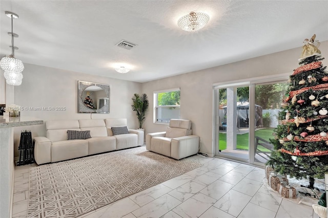 living area featuring visible vents, marble finish floor, and a textured ceiling