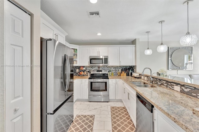 kitchen with a sink, decorative backsplash, white cabinets, appliances with stainless steel finishes, and marble finish floor