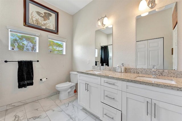 full bathroom featuring a sink, toilet, marble finish floor, and double vanity