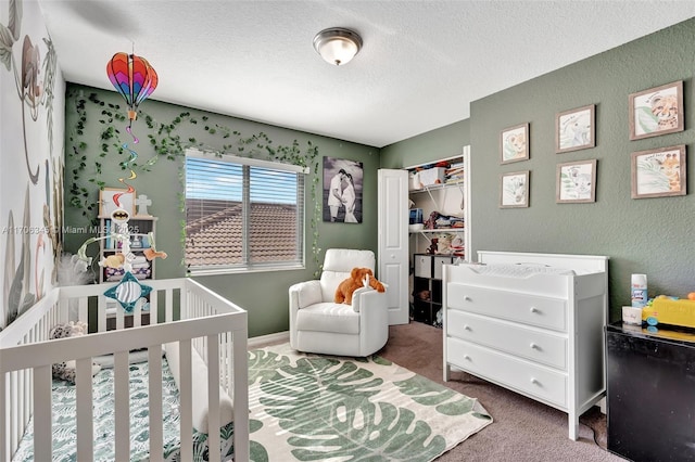 carpeted bedroom featuring a crib, a textured wall, a closet, and a textured ceiling