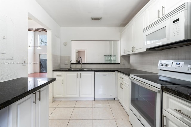 kitchen featuring sink, light tile patterned floors, dark stone countertops, white appliances, and white cabinets