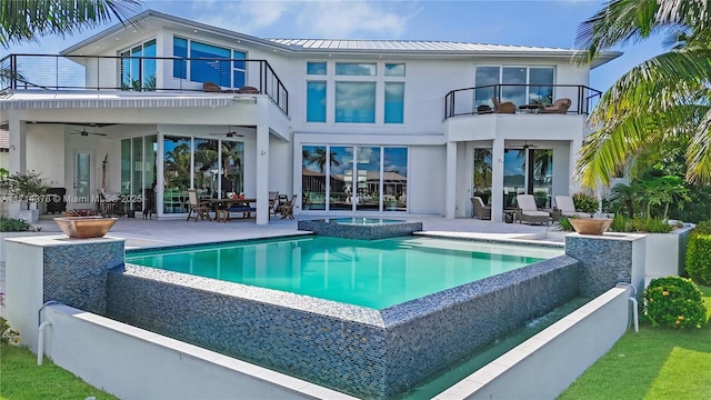 rear view of property with a swimming pool with hot tub, ceiling fan, a patio, and a balcony