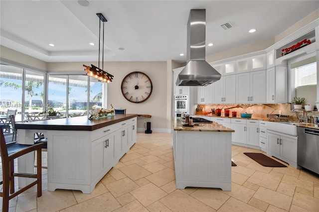 kitchen with white cabinetry, stainless steel appliances, a center island, and hanging light fixtures