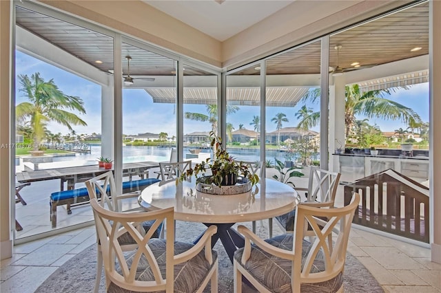 sunroom with a water view and ceiling fan