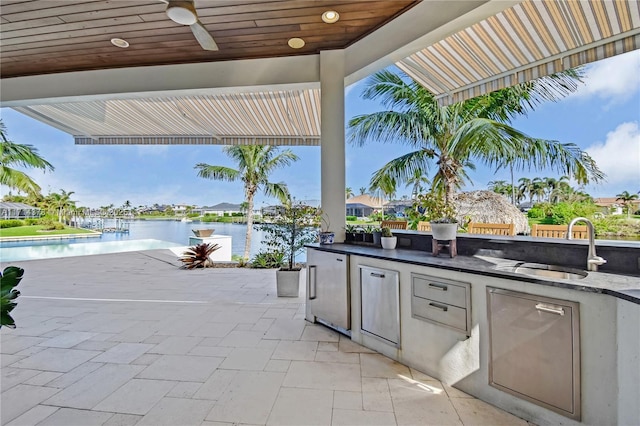 view of patio / terrace with exterior kitchen, a water view, sink, and ceiling fan