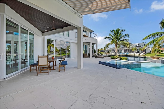 view of pool with an in ground hot tub, ceiling fan, a water view, and a patio area