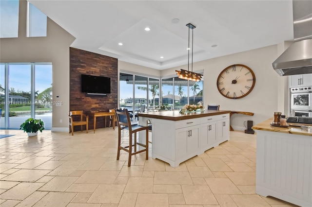 kitchen featuring a kitchen breakfast bar, double oven, a kitchen island, pendant lighting, and white cabinets