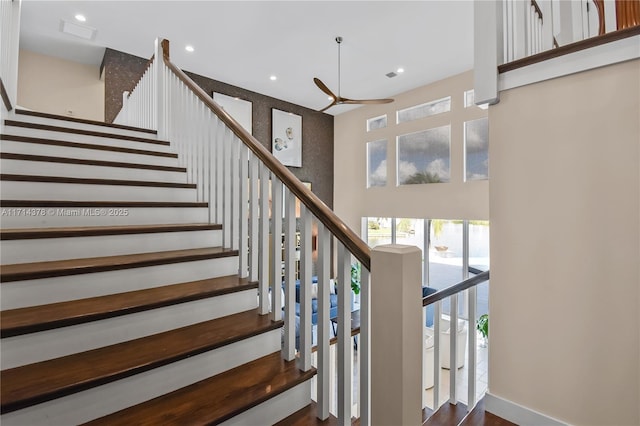 staircase with a towering ceiling and ceiling fan