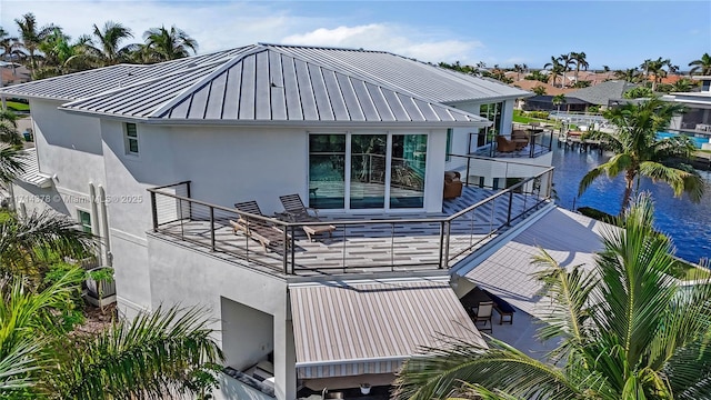 rear view of property featuring a balcony and a water view