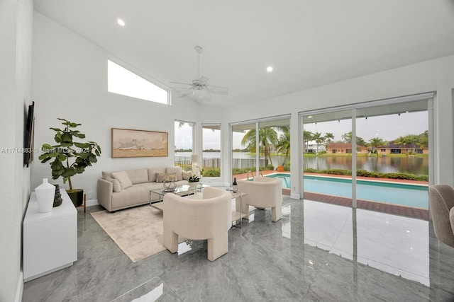 living room featuring ceiling fan and a water view