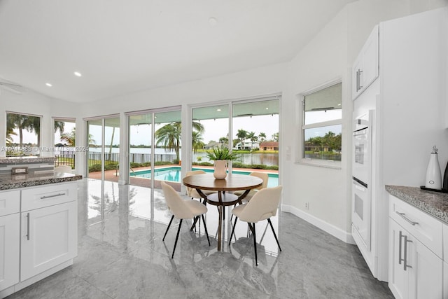 sunroom featuring a water view and vaulted ceiling