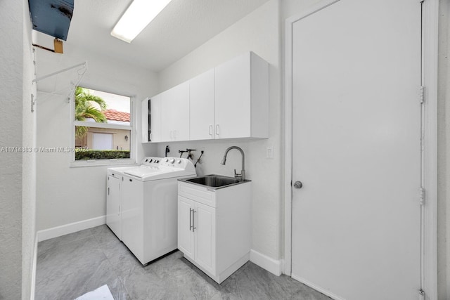 laundry area with cabinets, separate washer and dryer, and sink