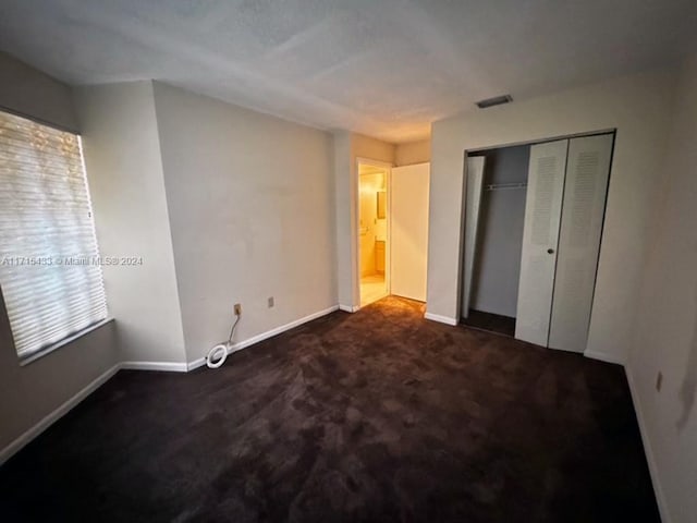 unfurnished bedroom featuring dark colored carpet and a closet