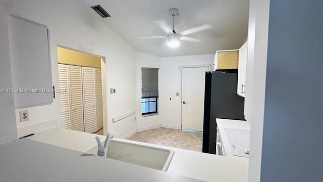 kitchen featuring white cabinets, black fridge, sink, and ceiling fan