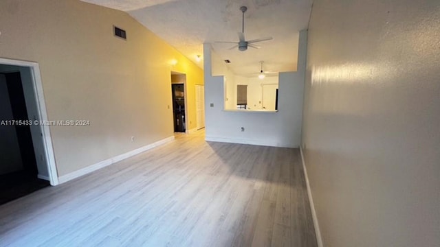 unfurnished living room featuring ceiling fan, light wood-type flooring, and vaulted ceiling