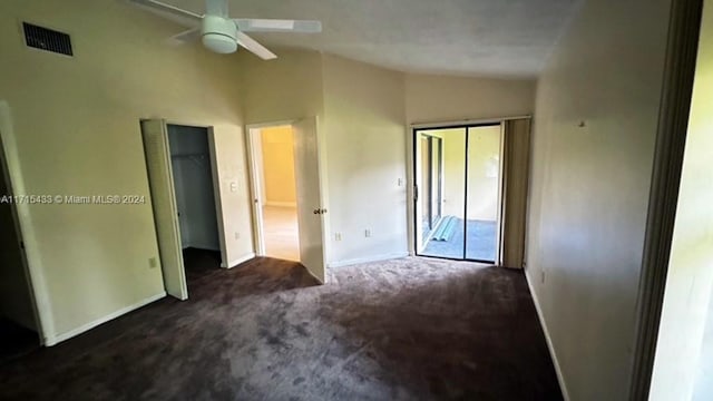 unfurnished bedroom with two closets, ceiling fan, lofted ceiling, and dark colored carpet