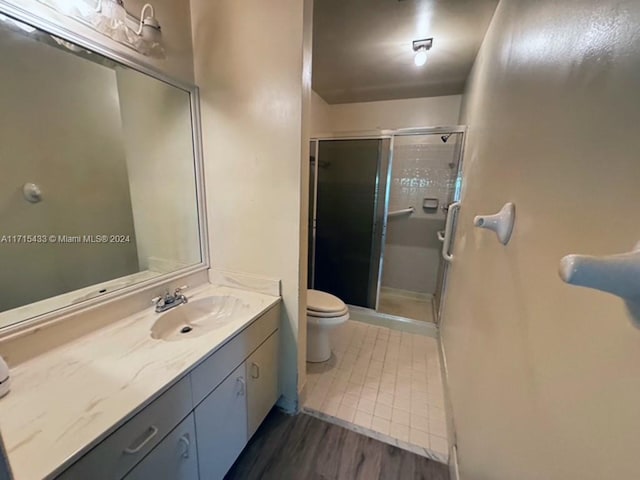 bathroom with toilet, vanity, hardwood / wood-style floors, and walk in shower