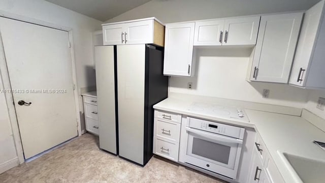 kitchen featuring white cabinets, white appliances, lofted ceiling, and sink