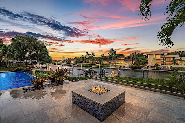 patio terrace at dusk featuring a water view and an outdoor fire pit